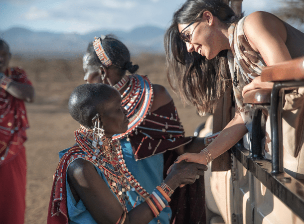 Tourists being greeted by a Maasai woman